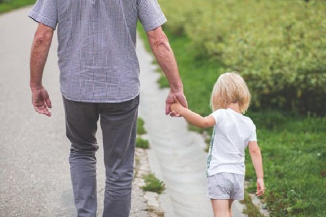 grandpa walking with granddaughter hand in hand 
